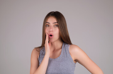 Shocked face of woman shouting WOW, isolated on studio background with copy space. Shock content. Girl looks with terrified expression, shocking news. Woman shocked face with open mouth and big eyes.