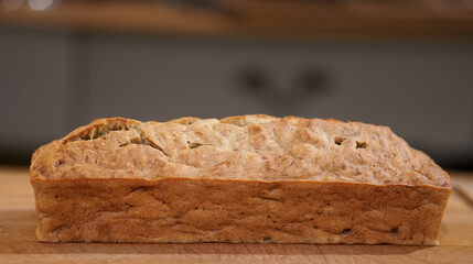 Side view of a banana bread loaf resting on a wooden cupboard.