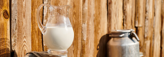 object photo of churn and jar of fresh milk placed outside of village house on modern farm, banner