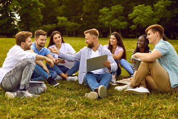 International multiethnic students do homework research group project assignment, meet outdoors on university campus lawn, cooperate, study information, use modern laptop computer notebook PC device