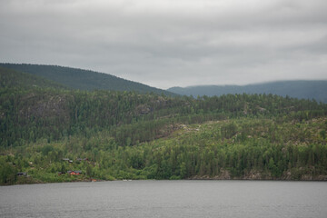 Landscape with a lake and green trees in the mountains and typical Norwegian wooden mountain houses.