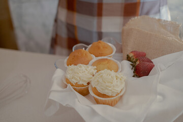 On the table are cupcakes, showcasing the artistry of a pastry baker. The kitchen table displays the tools and ingredients of a pastry chef, ready for culinary creations.