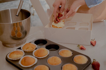A female pastry chef packs cupcakes into packaging for shipping to customers, showcasing homemade baking. Experience the essence of small-scale, eco-friendly baking with gluten-free and sugar-free 