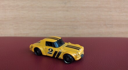 Miniature yellow car toy on red background with copy space for text