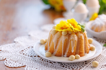 Easter bundt cake, Babka covered with icing, decorated with chocolate eggs and primrose flowers on a festive table, with copy space. - 757405903
