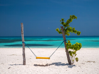 Une balançoire  artisanale posée sur une plage paradisiaque dans une île tropicale.