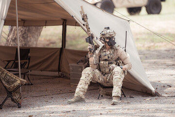 Portrait of soldiers in camouflage uniforms hold weapons in front of a field tent, Prepare for...