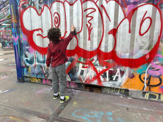 Amsterdam, Netherlands, February 17, 2024: A young guy paints graffiti on a wall