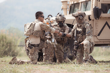 Group of soldiers in camouflage uniforms hold weapons in a jltv car, Plan and prepare for combat...