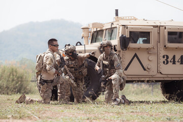 Group of soldiers in camouflage uniforms hold weapons in a jltv car, Plan and prepare for combat...