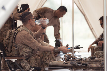 Group of soldiers in camouflage uniforms hold weapons in a field tent, Plan and prepare for combat...