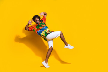 Fototapeta na wymiar Full length photo of optimistic funny guy wear hawaii print shirt dancing on summer party isolated on vibrant yellow color background
