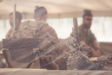 Group of soldiers in camouflage uniforms hold weapons in a field tent, Plan and prepare for combat...