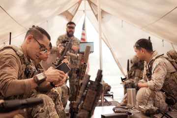 Group of soldiers in camouflage uniforms hold weapons in a field tent, Plan and prepare for combat...