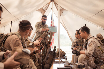 Group of soldiers in camouflage uniforms hold weapons in a field tent, Plan and prepare for combat...