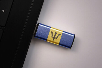 usb flash drive in notebook computer with the national flag of barbados on gray background.