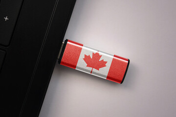 usb flash drive in notebook computer with the national flag of canada on gray background.