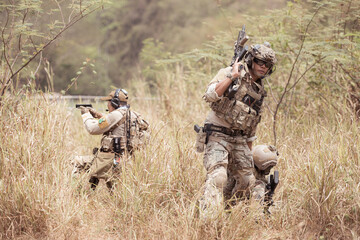 Soldiers in camouflage military uniforms carrying weapons, Reconnaissance missions in the tropical forest area with mission of helping those injured from being shot