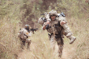 Soldiers in camouflage military uniforms carrying weapons, Reconnaissance missions in the tropical forest area with mission of helping those injured from being shot