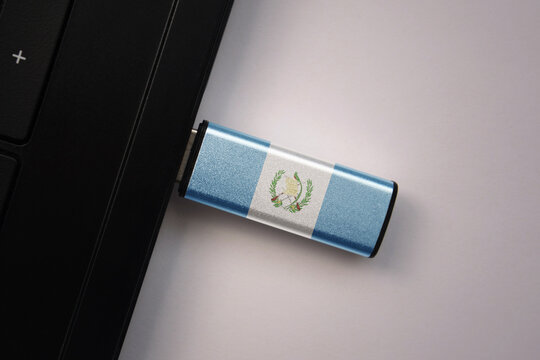 usb flash drive in notebook computer with the national flag of guatemala on gray background.