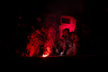 Group of soldiers in camouflage uniforms hold weapons with patrol missions at night