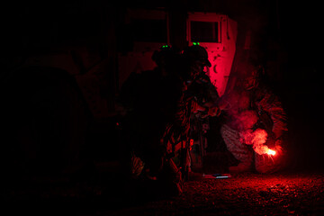 Group of soldiers in camouflage uniforms hold weapons with patrol missions at night