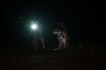 Group of soldiers in camouflage uniforms hold weapons with patrol missions at night