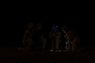 Fototapeta premium Group of soldiers in camouflage uniforms hold weapons with patrol missions at night