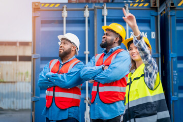 Portrait of Engineer or foreman team pointing up the future  with cargo container background at sunset. Logistics global import or export shipping industrial concept.