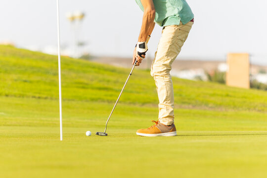 Unconventional golfer with blonde dreadlocks putting on green