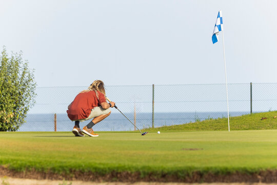 Unique golfer with dreadlocks preparing to putt