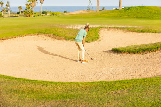 Unique golfer with dreadlocks playing in a sand bunker