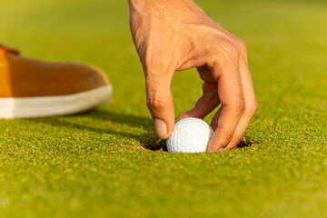 Unusual golfer with dreadlocks placing ball on green