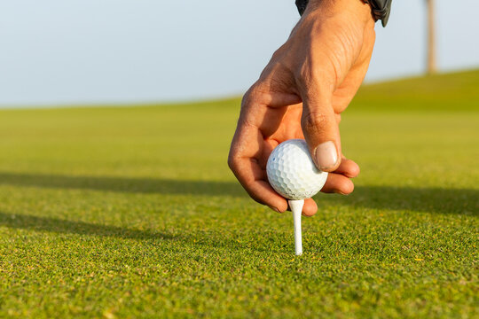 Anonymous golfer with dreadlocks placing ball on tee
