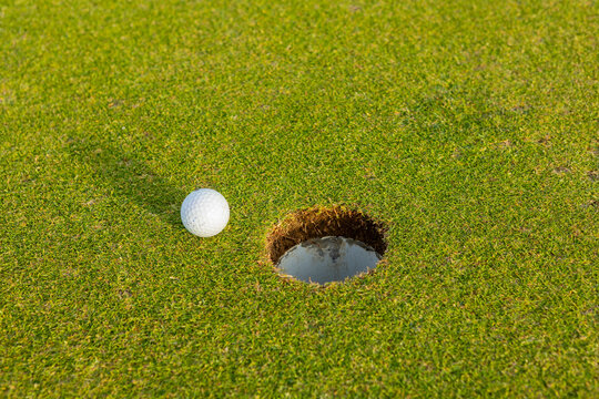 Close-up of golf ball near the hole on green grass