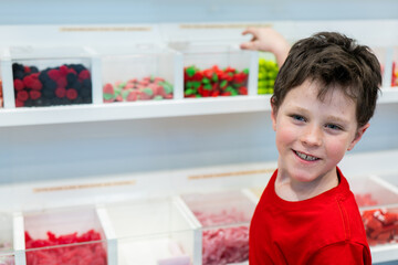 Boy smiling in a candy shop choosing sweets