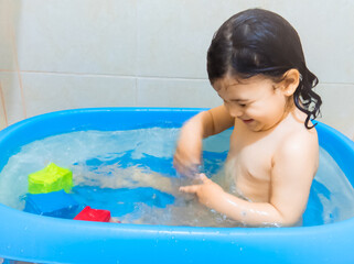 Hermosa niña blanca de dos años disfrutando su baño, sonriendo y jugando con el agua