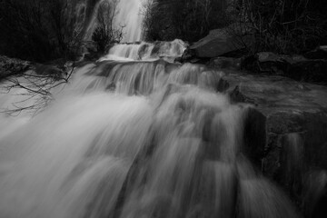 Smooth textures of the Rio Mundo Waterfall are accentuated in greyscale, capturing the serene flow of nature in motion
