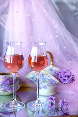 Two glasses of pink wine on a purple background