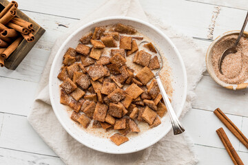 Top down view of a bowl of homemade cinnamon toast crispy cereal with milk.