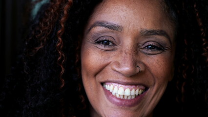 One happy middle-aged black woman close-up face smiling at camera. South American female person of...