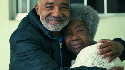 Adult South American black middle-aged son embracing elderly 80s gray-hair mother in loving tender...