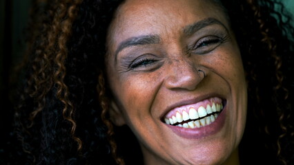 One happy South American black middle-aged woman authentic smile and laugh close-up face. 50s...