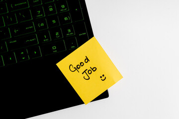 Top view of words Good job written on sticky note on keyboard over wooden background.