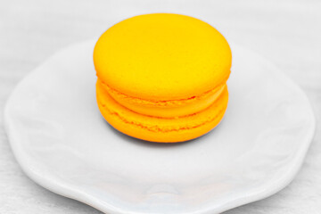 Macaroon on white plate in cafe. Macaron cake with orange fruit cream. Sweet food concept. Morning dessert. Orange macaron, isolated. Dessert assortment. French biscuit. - 757429796