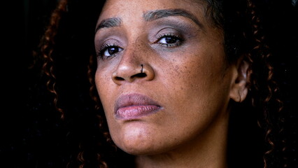 One serious black middle-aged woman close-up face looking at camera with intense gaze, upset judgemental expression of African American 50s lady