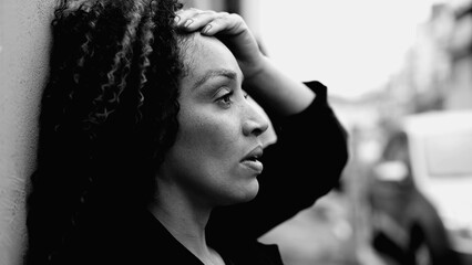Concerned African American middle-aged woman suffering in quiet despair outdoors in urban environment, person coping with mental anxiety, struggling with modern life, black and white - obrazy, fototapety, plakaty