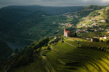 A view of a river and a village in the hills of the Douro Valley in northern Portugal. - obrazy, fototapety, plakaty