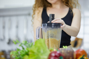 closeup woman hands mixing fruits from portable blender and preparing smoothie in kitchen