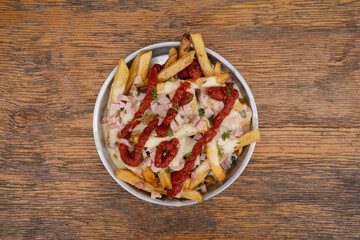 Fried potatoes with ham, mozzarella cheese, ketchup, onion and fresh oregano in a metal dish with a...